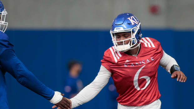 Kansas junior quarterback Jalon Daniels (6) slaps a teammates hand practice Tuesday morning in Lawrence.